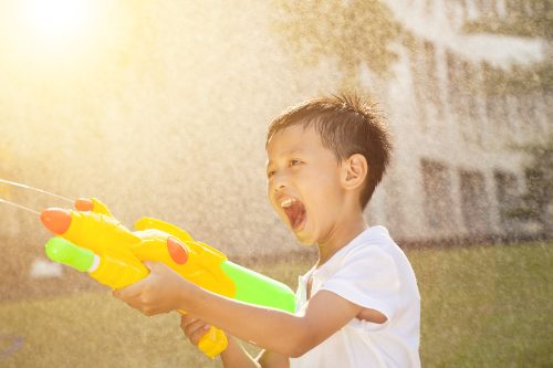 Little,Boy,Shouting,And,Playing,Water,Guns,In,The,Park